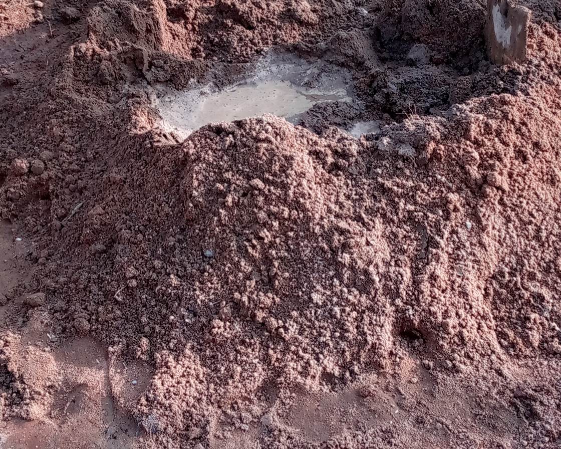 Montón de arena y cemento mezclados en el suelo, con un hueco en el centro lleno de agua, la forma de volcán del amasado a mano
