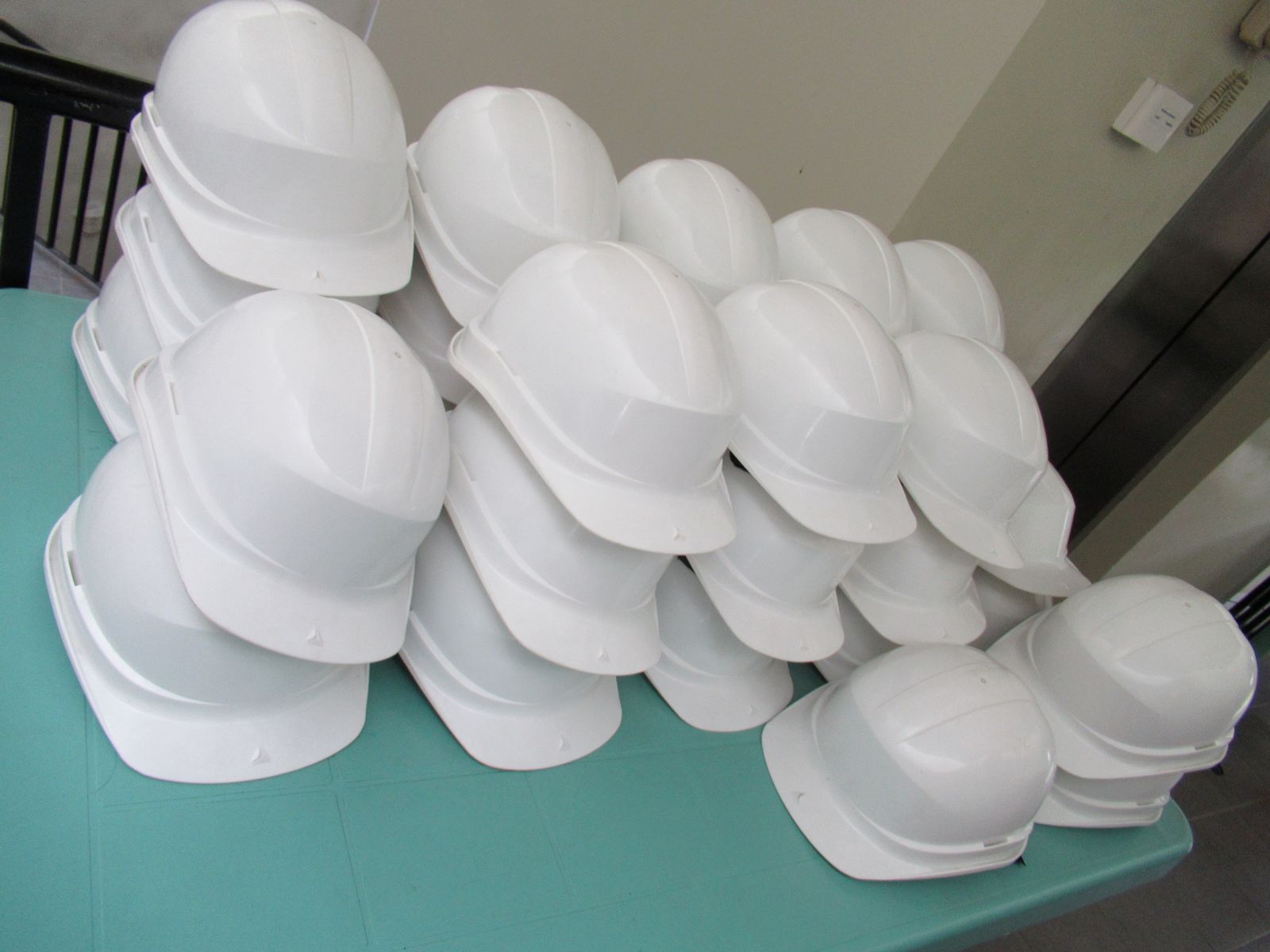 Cascos de obra blancos apilados unos sobre otros encima de una mesa